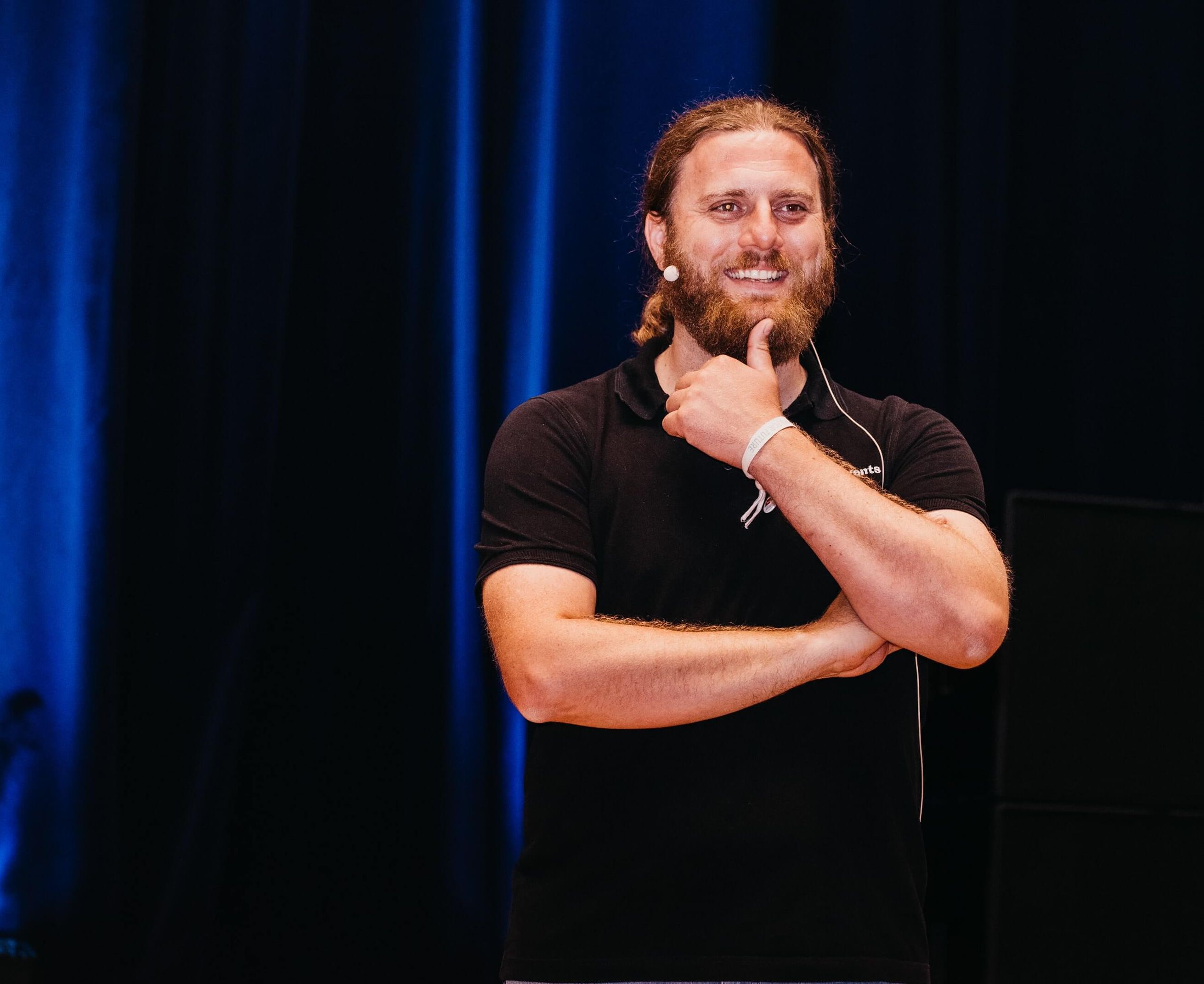 Ein bärtiger Mann lachend Arme verschränkt und Daumen am Kinn - es handelt sich um Peter Götz im Scaled Professional Scrum Training